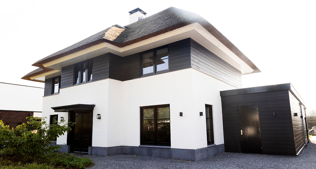 wit huis zwarte kozijnen rieten kap luxe